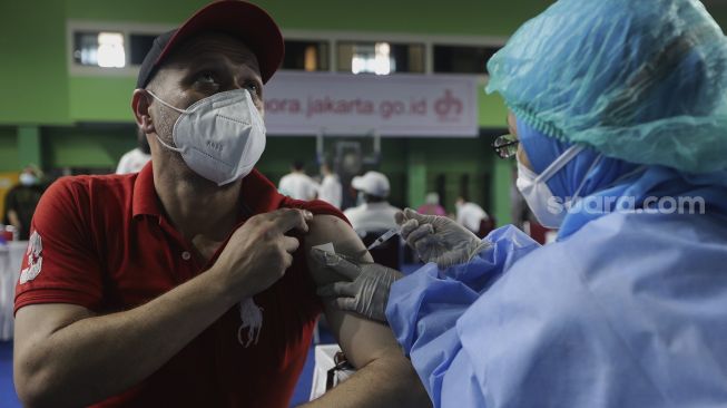 Seorang pencari suaka mendapatkan vaksinasi COVID-19 Sinopharm di GOR Bulungan, Kebayoran Baru, Jakarta, Kamis (7/10/2021). [Suara.com/Angga Budhiyanto]