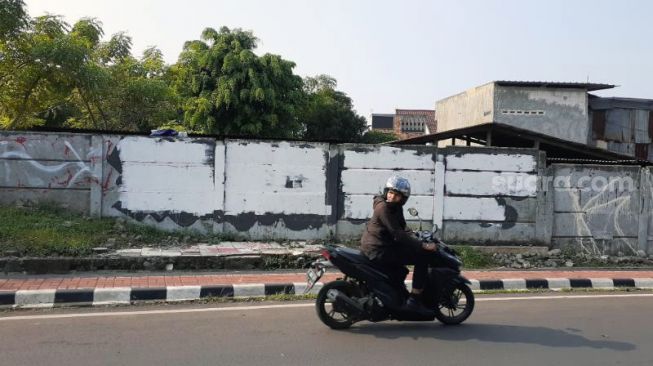 Grafiti satire Koruptor Dirangkul, Rakyat Kecil Dipukul di Jalan Taman Bintaro Barat, Pesanggrahan, Jakarta Selatan, kekinian telah dihapus dengan cat warna putih, Kamis (7/10/2021). [SuaraJakarta.id/Wivy Hikmatullah]