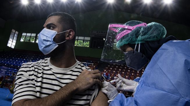 Seorang pencari suaka mendapatkan vaksinasi COVID-19 Sinopharm di GOR Bulungan, Kebayoran Baru, Jakarta Selatan, Kamis (7/10/2021). ANTARA FOTO/Sigid Kurniawan