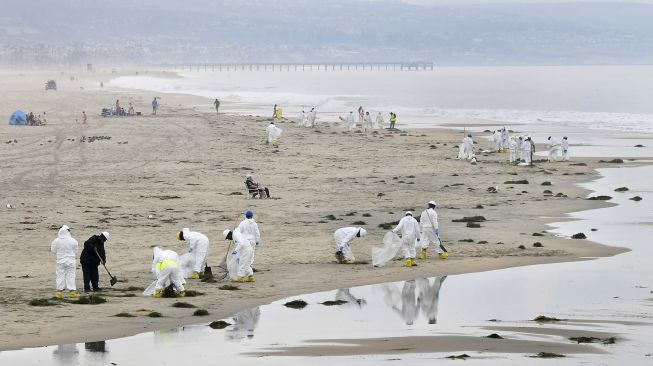 Kru pembersihan bekerja di Pantai Newport, California, pada (7/10/2021). [Frederic J. BROWN / AFP]