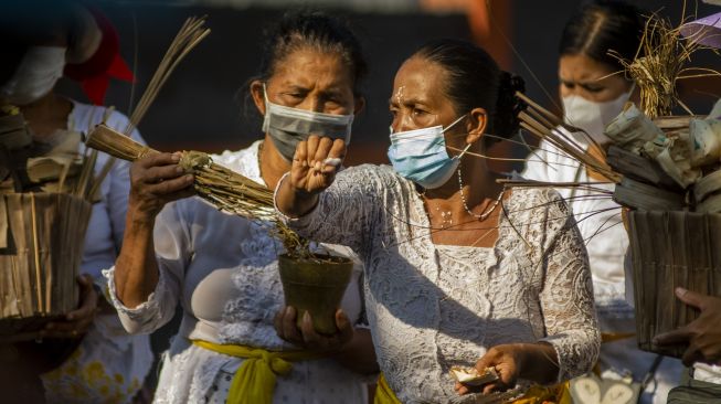 Petugas memercikkan air suci saat ritual Ngulapin (pembangkitan roh) pada upacara Ngaben Ngerit di Pura Prajapati, Palu, Sulawesi Tengah, Kamis (7/10/2021). [ANTARA FOTO/Basri Marzuki]