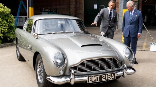 Daniel Craig memaparkan kerennya Aston Martin DB5 kepada Prince of Wales, Pangeran Charles (kanan). Sang pangeran bertemu dengan pemeran Agen 007 saat tur ke lokasi syuting film James Bond ke-25 di Pinewood Studios, Iver Heath, barat London (20/6/2019) [AFP/POOL/Niklas Halle'n].