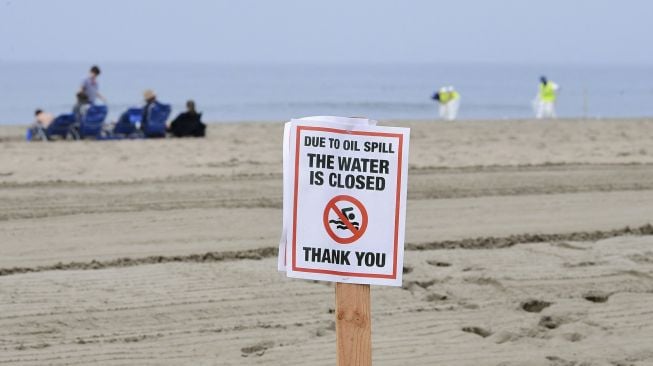 Sebuah tanda menunjukkan penutupan kawasan air karena tumpahan minyak terlihat di Pantai Newport, California, pada (7/10/2021). [Frederic J. BROWN / AFP]