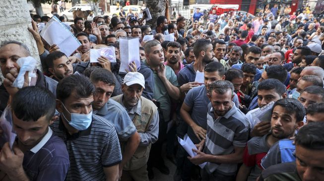 Warga Palestina berkumpul untuk mengajukan izin kerja di Israel, di kamp pengungsi Jabalia, Jalur Gaza, pada (6/10/2021). [Mahmud hams / AFP]