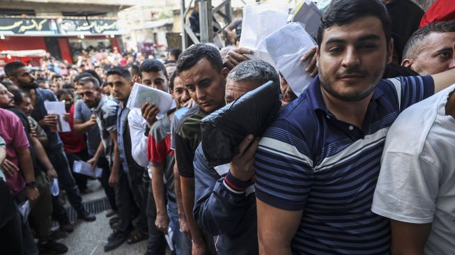 Warga Palestina berkumpul untuk mengajukan izin kerja di Israel, di kamp pengungsi Jabalia, Jalur Gaza, pada (6/10/2021). [Mahmud hams / AFP]