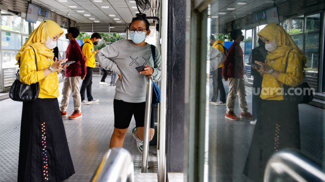 Penumpang mengisi saldo kartu JakLingko di Halte Bundaran HI, Jakarta Pusat, Minggu (10/10/2021). [Suara.com/Alfian Winanto]