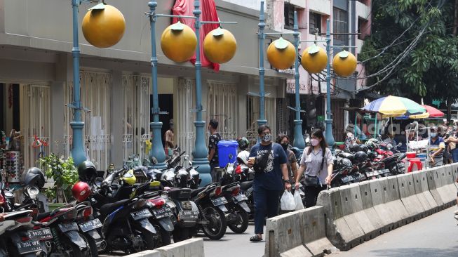 Pejalan kaki melintas di kawasan Glodok, Jakarta Barat, Minggu (10/10/2021). [Suara.com/Alfian Winanto]
