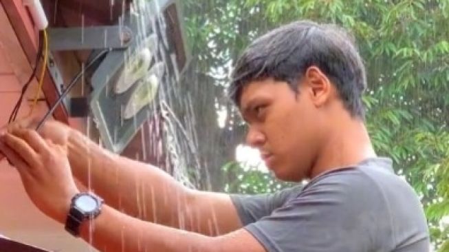 Di Bawah Guyuran Hujan, Pria Ini Fokus Kerja Tanpa Basah, Warganet: Abangnya Waterproof