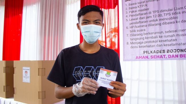 Warga menunjukan surat suara Pilkades setelah mencoblos di TPS 04 Desa Bojong Kamal, Kabupaten Tangerang, Banten. Minggu 10/10.  ( Suara.com/ Hilal Rauda Fiqry) 