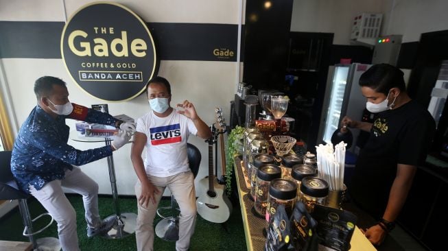 Petugas Dokkes Polda Aceh (kiri) memberikan suntikan vaksin COVID-19 Sinovac kepada pengunjung salah satu warung kopi (warkop) di Banda Aceh, Aceh, Minggu (10/10/2021).  ANTARA FOTO / Irwansyah Putra

