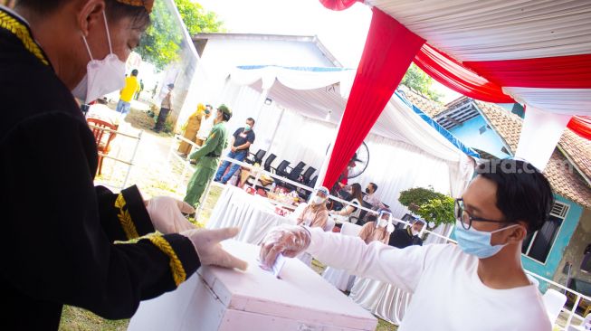Warga memasukan surat suara ke kotak yang disediakan petugas TPS di TPS 04 Desa Bojong Kamal, Kabupaten Tangerang, Banten, Minggu (10/10). [Suara.com / Hilal Rauda Fiqry]
