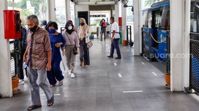Penumpang beraktivitas di Halte Bundaran HI, Jakarta Pusat, Minggu (10/10/2021). [Suara.com/Alfian Winanto]