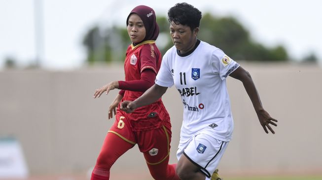 Pesepak bola putri Babel Susilawati (kanan) berebut bola dengan pesepak bola putri DKI Jakarta Sri Devi (kiri) saat bertanding pada perebutan tempat ketiga Sepak Bola Putri PON Papua di Stadion Katalpal, Kabupaten Merauke, Papua, Senin (11/10/2021). ANTARA FOTO/Galih Pradipta
