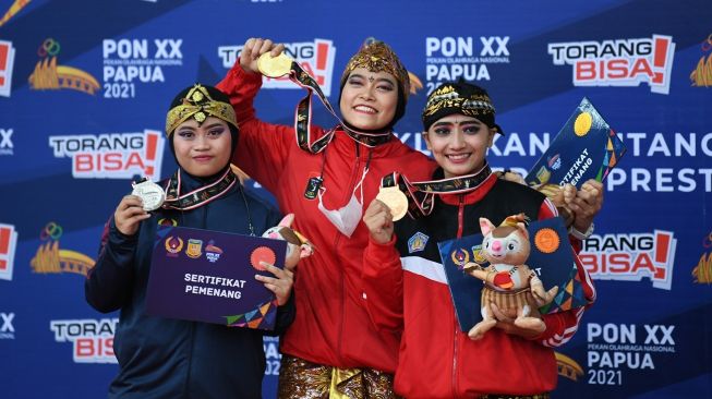 Pesilat putri DKI Jakarta Puspa Arumsari (tengah) bersama pesilat putri Jawa Barat Risya Gunawan (kiri) dan pesilat putri Bali Ni Kadek Astini (kanan) memperlihatkan medalinya saat penyerahan medali Pencak silat kategori Seni Tunggal Putri PON Papua di Gor Toware, Kabupaten Jayapura, Papua, Senin (11/10/2021). [ANTARA FOTO/Mohammad Ayudha]