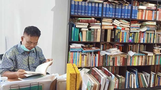 Cendikiawan Sakai, Mohamad Agar Kalipke (60) saat menunjukan koleksi buku-buku di perpustakaan mini rumahnya. [Suara.com/Panji Ahmad Syuhada]