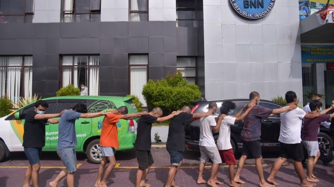 Petugas menggiring mahasiswa yang diamankan saat ungkap kasus di Kantor Badan Narkotika Nasional (BNNP) Provinsi Sumatera Utara, Percut Sei Tuan, Deliserdang, Sumatera Utara, Senin (11/10/2021). ANTARA FOTO/Fransisco Carolio