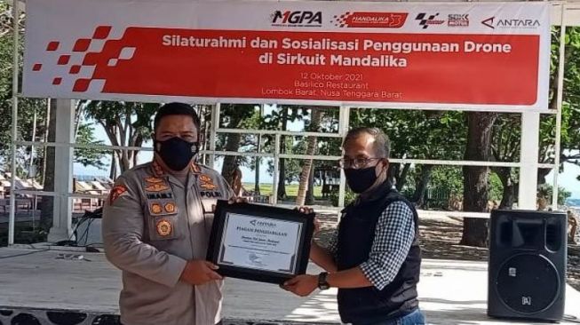 Kepala Biro Operasi Polda NTB Kombes Pol Imam Thobroni (kiri), menerima cenderamata dari Kepala Biro ANTARA NTB Riza Fahriza, dalam pertemuan bertajuk "Silaturahmi dan sosialisasi penggunaan drone di Sirkuit Mandalika", di kawasan wisata Senggigi, Kabupaten Lombok Barat, Selasa (12/10/2021) [ANTARA/Awaludin].