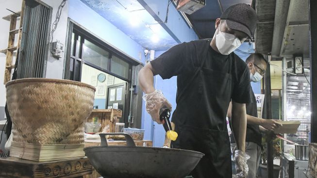 Mantan Penyidik KPK Juliandi Tigor Simanjuntak memasak nasi goreng di warung wilayah Pondok Melati, Bekasi, Senin (11/10/2021).  ANTARA FOTO