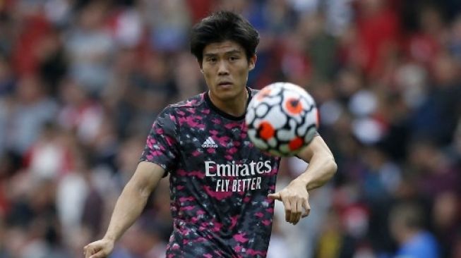 Pemain Arsenal Takehiro Tomiyasu melakukan pemanasan jelang pertandingan Liga Premier Inggris di Emirates Stadium. [AFP]