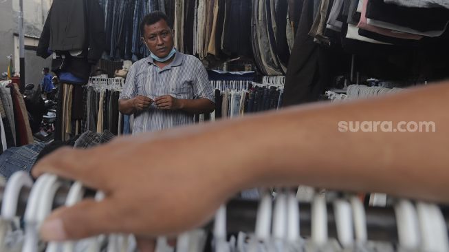 Seorang pedagang pakaian bekas layak pakai (thrifting) menunggu pembeli di Pasar Kebayoran Lama, Jakarta, Rabu (13/10/2021). [Suara.com/Angga Budhiyanto]