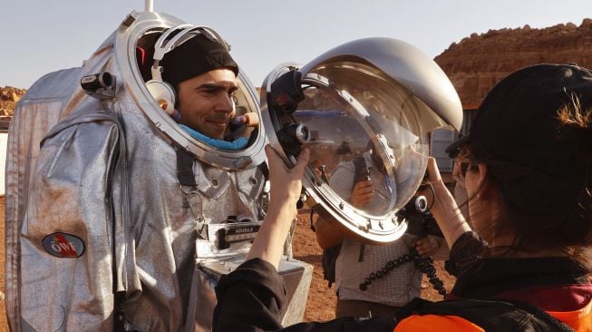 Teknisi membantu astronot dari tim Eropa dan Israel untuk mengenakan pakaian antariksa sebelum memulai misi pelatihan untuk planet Mars di sebuah situs yang mensimulasikan stasiun di luar lokasi di Kawah Ramon, Mitzpe Ramon, Gurun Negev, Israel, pada (10/10/2021). [JACK GUEZ / AFP]