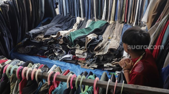 Seorang pedagang pakaian bekas layak pakai (thrifting) menunggu pembeli di Pasar Kebayoran Lama, Jakarta, Rabu (13/10/2021). [Suara.com/Angga Budhiyanto]