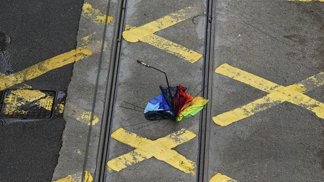 Payung yang rusak terlihat di jalan kawasan pusat bisnis di Hong Kong, pada (13/10/2021). [PETER PARKS / AFP]