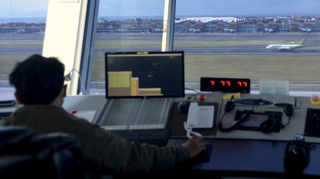 Petugas memantau dan mengatur pergerakan pesawat udara di menara Air Traffic Controller (ATC) Bandara Internasional I Gusti Ngurah Rai, Bali, Rabu (13/10/2021). [ANTARA FOTO/Fikri Yusuf]