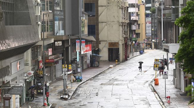 Seorang pejalan kaki melintasi jalan kosong di Kawasan Pusat Bisnis Hong Kong pada 13 Oktober 2021. [PETER PARKS / AFP]