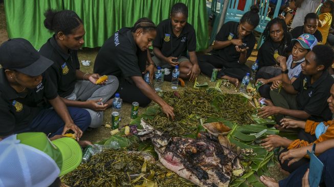 Atlet sepakbola putri Papua bersama warga menggelar pesta adat bakar batu di Kabupaten Merauke, Papua, Rabu (13/10/2021). [ANTARA FOTO/Galih Pradipta]