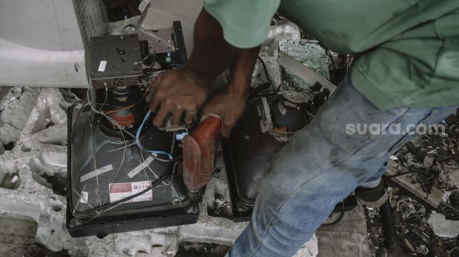 Pekerja membongkar layar monitor komputer di penampungan limbah elektronik di Legok, Kabupaten Tangerang, Banten, Kamis (14/10/2021). [Suara.com/Hilal Rauda Fiqry]