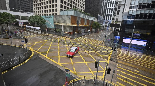 Sebuah taksi melintasi persimpangan kosong di kawasan pusat bisnis di Hong Kong, pada (13/10/2021). [PETER PARKS / AFP]