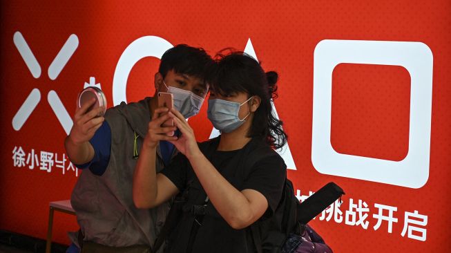 Pelanggan mengambil foto dalgona, permen gula renyah yang ditampilkan dalam serial Netflix Squid Game, di Shanghai, Cina, pada (12/10/2021). [HECTOR RETAMAL / AFP]