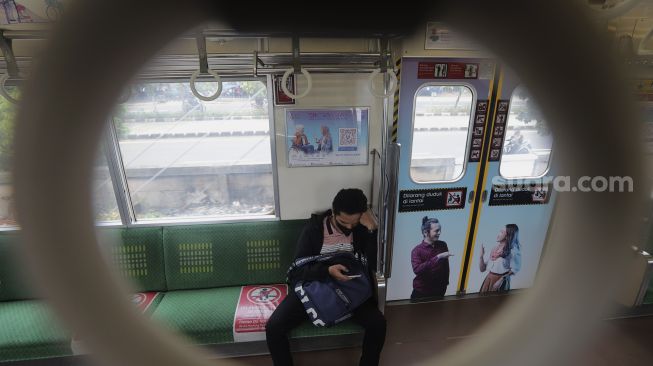 Seorang penumpang berada di dalam gerbong kereta commuter line yang dipasangi tanda kampanye inklusif tentang disabilitas yang berhenti di Stasiun Jatinegara, Jakarta, Jumat (15/10/2021). [Suara.com/Angga Budhiyanto]