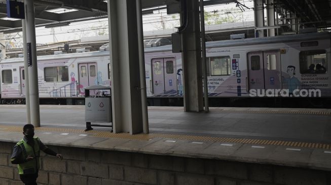 Petugas berjalan melintasi gerbong kereta commuter line yang dipasangi tanda kampanye inklusif tentang disabilitas yang berhenti di Stasiun Jatinegara, Jakarta, Jumat (15/10/2021). [Suara.com/Angga Budhiyanto]