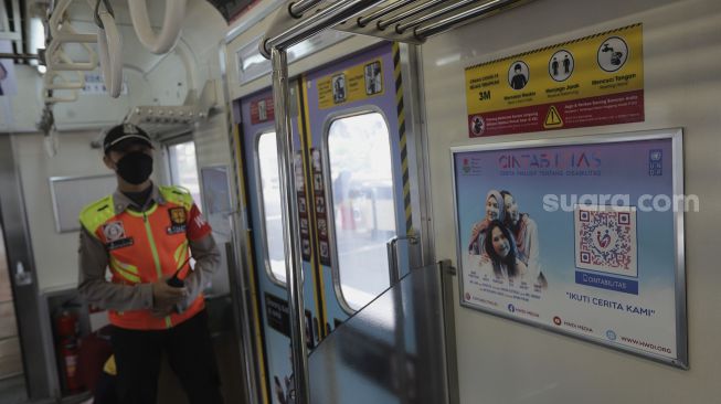 Petugas keamanan berjaga di gerbong kereta commuter line yang dipasangi tanda kampanye inklusif tentang disabilitas yang berhenti di Stasiun Jatinegara, Jakarta, Jumat (15/10/2021). [Suara.com/Angga Budhiyanto]