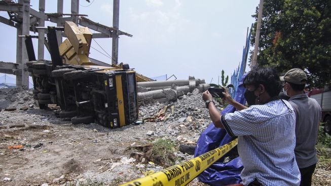 Warga memotret alat berat crane yang jatuh menimpa rumah warga di Pancoran Mas, Depok, Jawa Barat, Jumat (15/10/2021).  ANTARA FOTO/Asprilla Dwi Adha