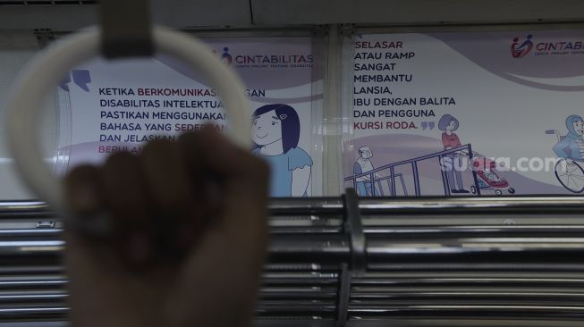 Tanda kampanye inklusif tentang disabilitas terpasang di salah satu gerbong kereta commuter line yang berhenti di Stasiun Jatinegara, Jakarta, Jumat (15/10/2021). [Suara.com/Angga Budhiyanto]