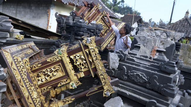 Warga mengamati puing-puing bangunan tempat ibadah yang rusak akibat gempa di kawasan Besakih, Karangasem, Bali, Sabtu (16/10/2021). [ANTARA FOTO/Fikri Yusuf]