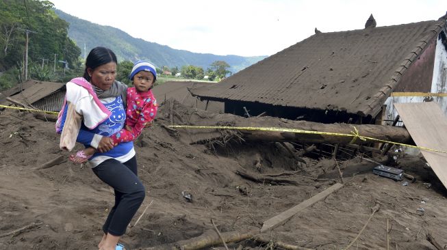 Warga berjalan di dekat rumah yang rusak tertimbun longsoran bukit akibat gempa di kawasan Trunyan, Kintamani, Bangli, Bali, Sabtu (16/10/2021). [ANTARA FOTO/Fikri Yusuf]