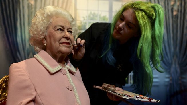 Seniman studio Emma Meehan memberikan sentuhan akhir pada patung lilin baru Ratu Elizabeth II Inggris di Madame Tussauds, Blackpool, Inggris, pada (14/10/2021). [PAUL ELLIS / AFP]