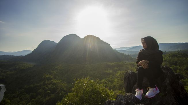 Pengunjung menikmati pemandangan dari atas wisata Bukit Batu Langara di kawasan Geopark Meratus, Kecamatan Loksado, Kabupaten Hulu Sungai Selatan, Kalimantan Selatan, Minggu (17/10/2021). [ANTARA FOTO/Bayu Pratama S]