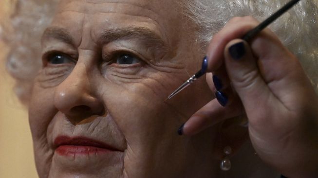 Seniman studio Emma Meehan memberikan sentuhan akhir pada patung lilin baru Ratu Elizabeth II Inggris di Madame Tussauds, Blackpool, Inggris, pada (14/10/2021). [PAUL ELLIS / AFP]