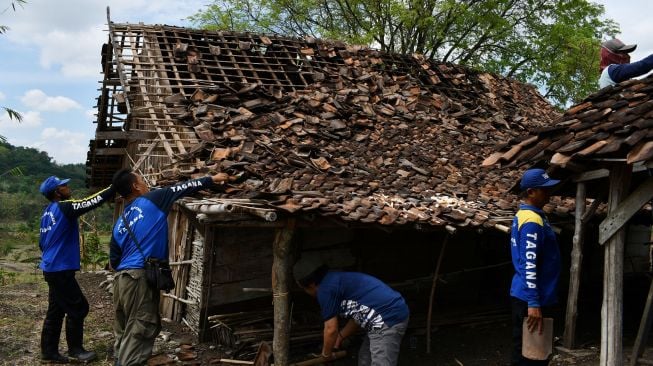 Anggota Taruna Siaga Bencana (Tagana) merapikan genteng pada rumah yang rusak akibat puting beliung di Desa Sumberbendo, Saradan, Kabupaten Madiun, Jawa Timur, Senin (18/10/2021). ANTARA FOTO/Siswowidodo
