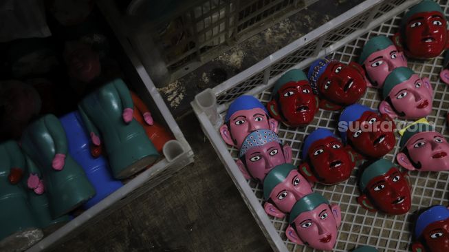 Miniatur topeng ondel-ondel tersimpan di toko miniatur ondel-ondel di Jalan Gang 3, Pondok Kopi, Kecamatan Duren Sawit, Jakarta, Senin (18/10/2021). [Suara.com/Angga Budhiyanto]