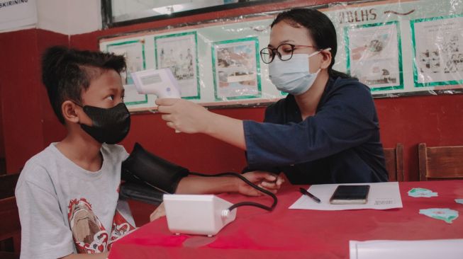 Petugas medis memeriksakan kesehatan siswa sekolah dasar sebelum mendapatkan vaksinasi Covid-19 Pfizer di SDN Karawaci 5, Kota Tangerang, Banten. Senin 18/10. ( Suara.com/ Hilal Rauda Fiqry)