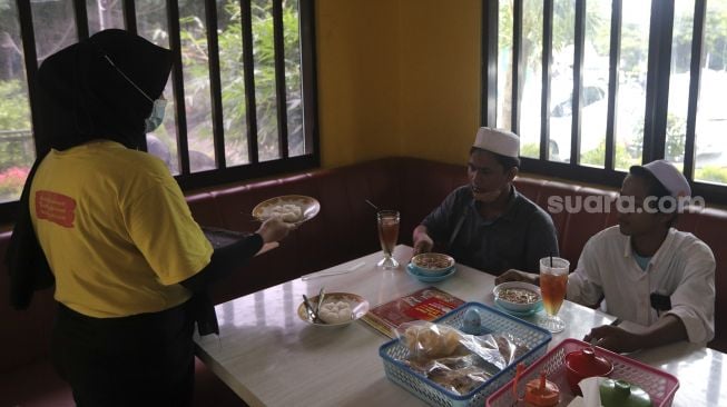 Pramusaji mengantarkan makanan gratis kepada pengunjung di Soto Seger Boyolali Hj. Amanah, Lebak Bulus, Jakarta, Selasa (19/10/2021). [Suara.com/Angga Budhiyanto]