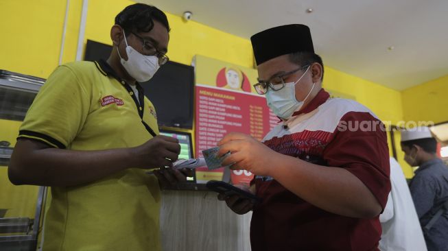 Warga menunjukkan kartu tanda penduduk kepada petugas untuk mendapatkan makanan gratis di Soto Seger Boyolali Hj. Amanah, Lebak Bulus, Jakarta, Selasa (19/10/2021). [Suara.com/Angga Budhiyanto]