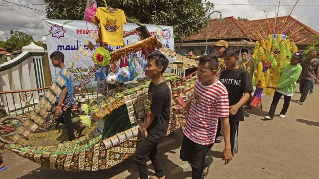 Sejumlah warga menggotong barang sedekah saat Perayaan Maulid Nabi Muhammad di Kampung Sukalila, Kelapa Dua, Serang, Banten, Selasa (19/10/2021). [ANTARA FOTO/Asep Fathulrahman]