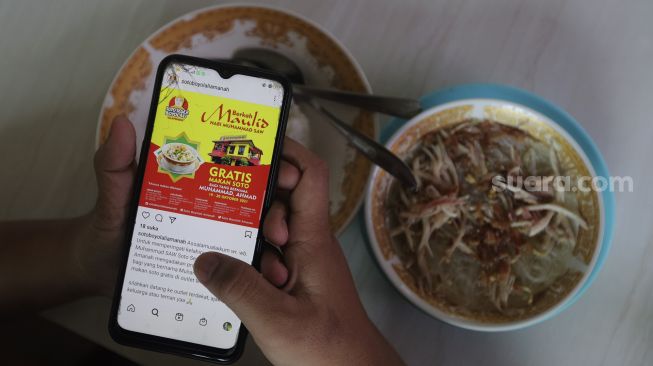 Warga menunjukkan sebaran promo makan gratis melalui gawainya di Soto Seger Boyolali Hj. Amanah, Lebak Bulus, Jakarta, Selasa (19/10/2021). [Suara.com/Angga Budhiyanto]